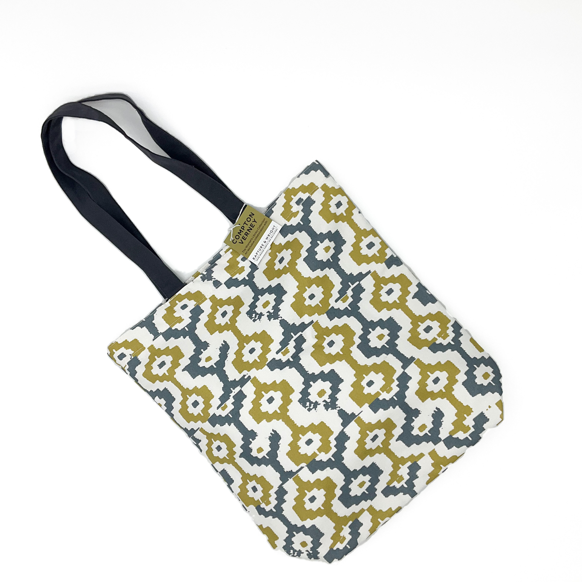 A tote bag featuring a grey and yellow geometric pattern with grey handles. The bag has a brown and white Compton Verney swing ticket on it.