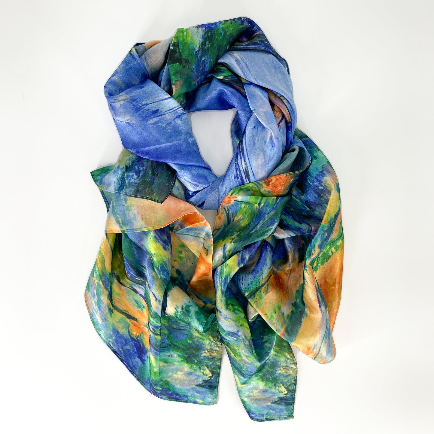 A silk scarf laid out in a knot shape with shades of blue, orange, green and yellow from the Cezanne painting.