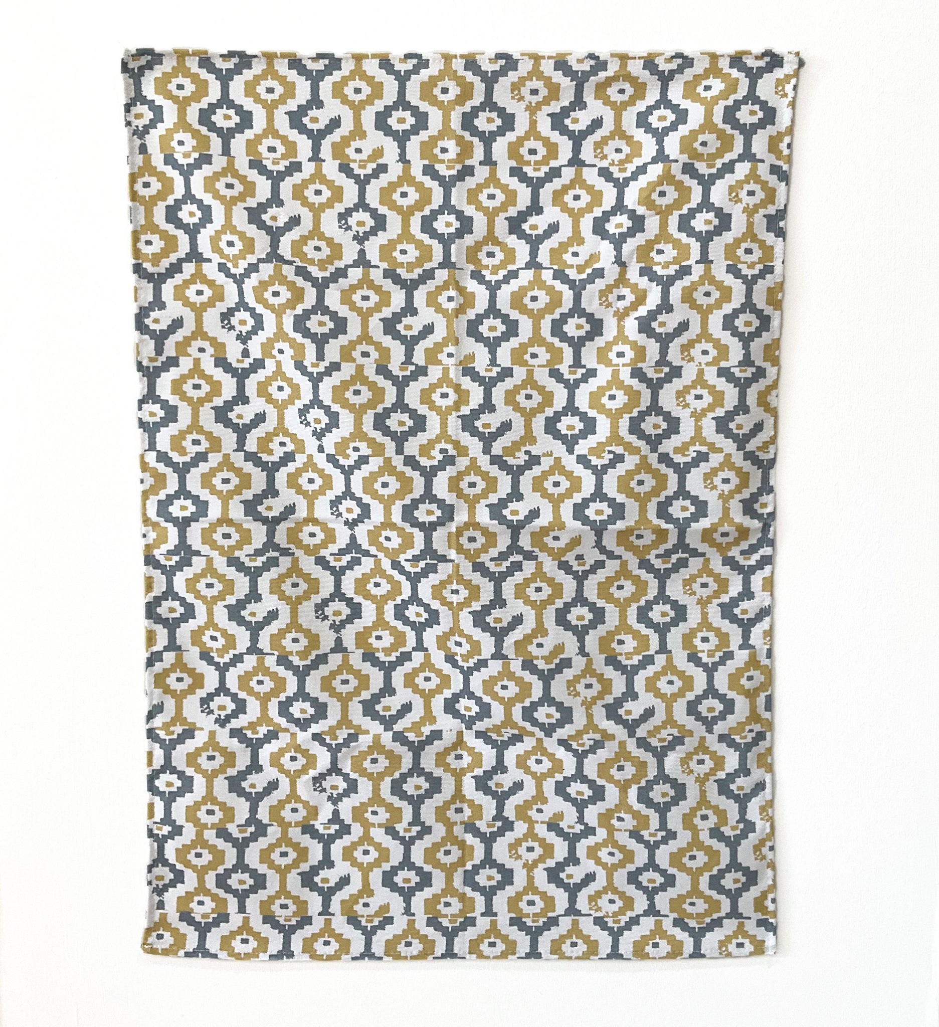 A tea towel featuring a grey and yellow geometric pattern on a white background.