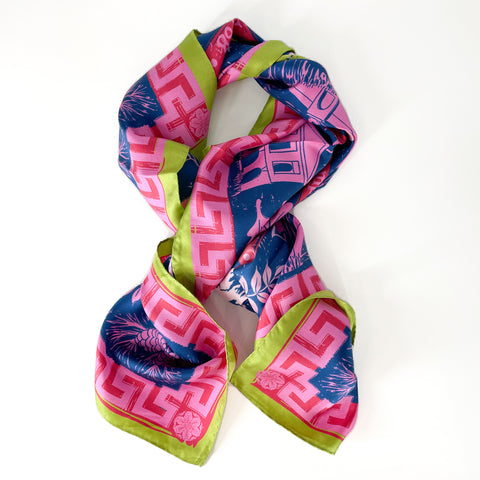 A silk scarf laid out in a knot shape with shades of pink, light green, dark blue and red from the geometric design.